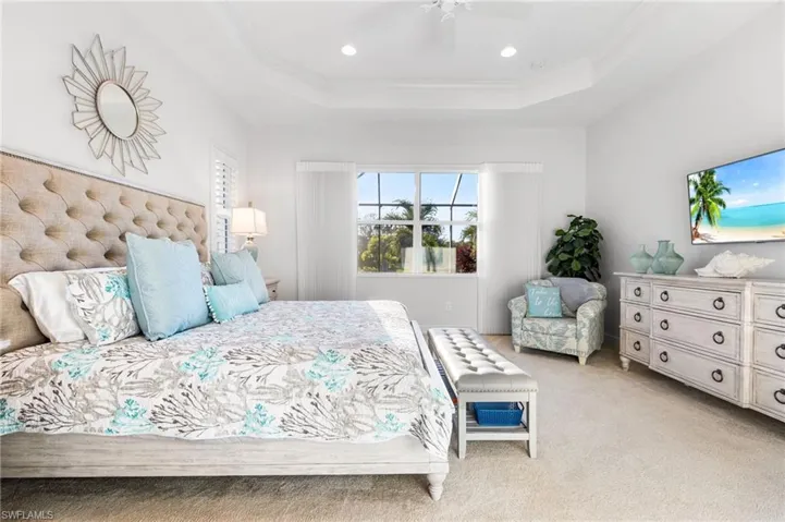 Bedroom featuring light carpet, ornamental molding, a tray ceiling, recessed lighting, and ceiling fan