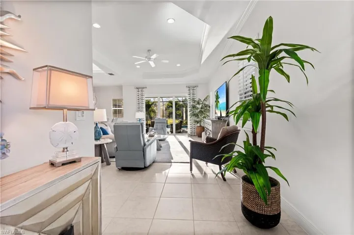 Living room featuring a tray ceiling, light tile patterned flooring, recessed lighting, and ceiling fan