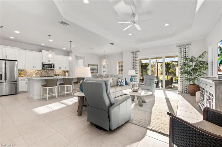 Living room featuring ornamental molding, recessed lighting, light tile patterned floors, a raised ceiling, and ceiling fan