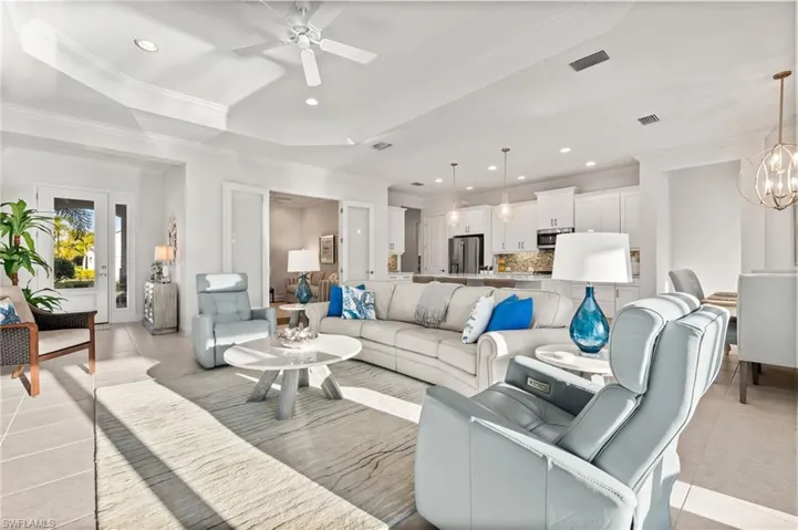 Living area with visible vents, ornamental molding, recessed lighting, light tile patterned floors, and a raised ceiling