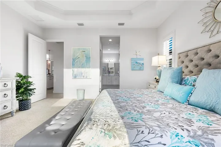 Bedroom with a tray ceiling, ornamental molding, visible vents, and light carpet