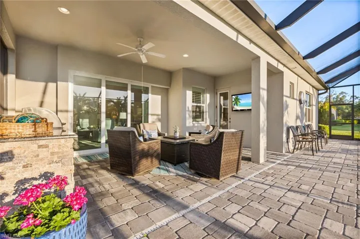 View of patio with an outdoor kitchen, a lanai, and a ceiling fan