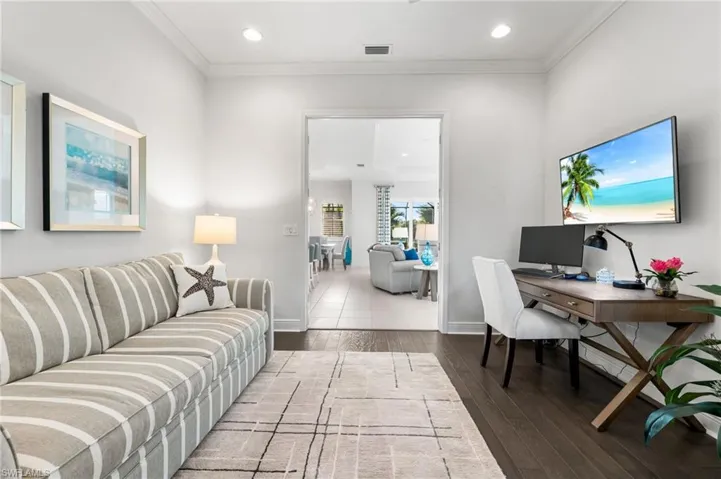 Living area with visible vents, baseboards, wood finished floors, and ornamental molding