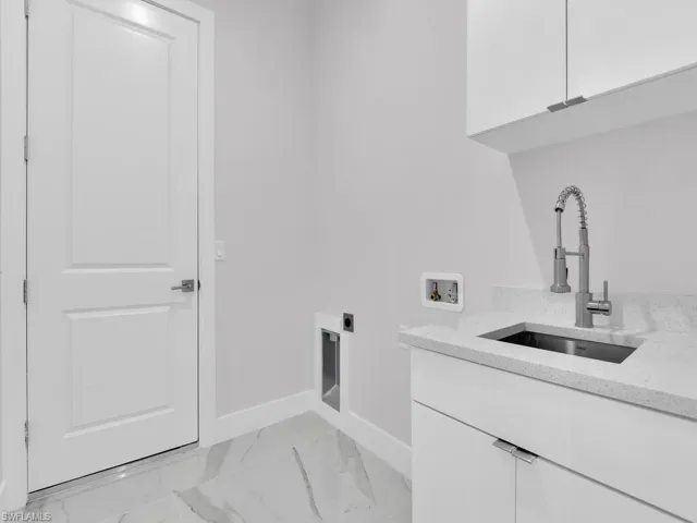 Washroom with cabinets, hookup for a washing machine, sink, and hookup for an electric dryer