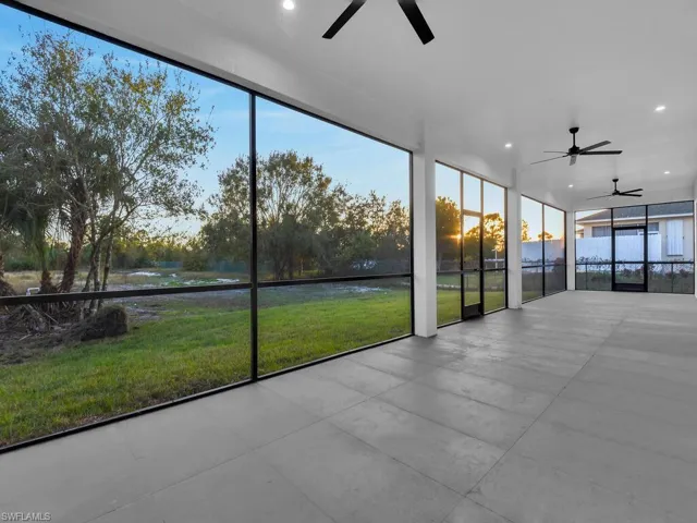 Unfurnished sunroom featuring a backyard, a healthy amount of sunlight, and 3 ceiling fan