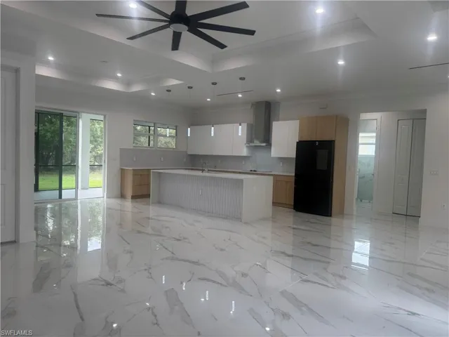 Kitchen with a center island with sink, a raised ceiling, modern cabinets, pantry, light countertops, and white cabinetry