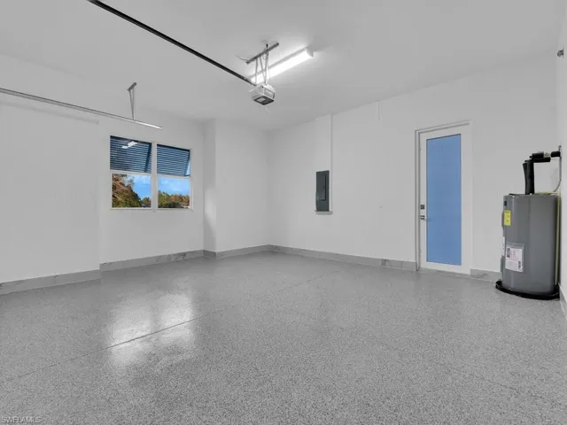 Garage featuring water heater, a garage door opener, and electric panel