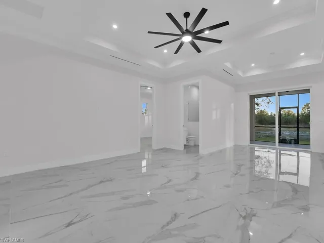 Living room with a raised ceiling and ceiling fan, porcelain tile floor, screened lanai in the back