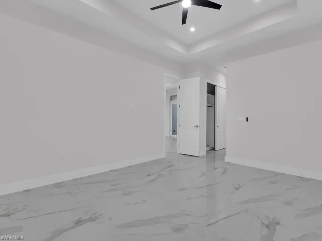 Primary bedroom featuring a tray ceiling and ceiling fan, California closet