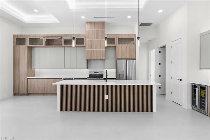 Kitchen featuring a central island with slatted wood paneling, white countertops, built-in stainless steel appliances, and integrated wood-finish cabinetry