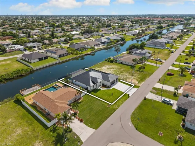 Waterfront property featuring a screened-in pool and attached spa, a dock, and a paver driveway