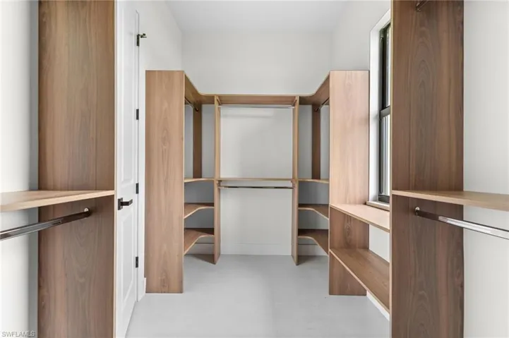 Custom closet system featuring wood-finish shelving, integrated hanging rods, and a window