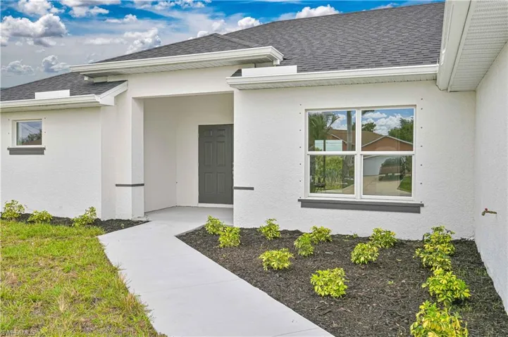 Doorway to property featuring roof with shingles and stucco siding
