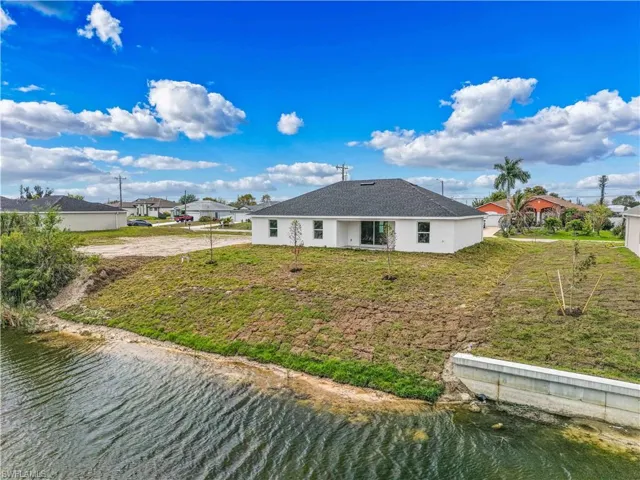 Rear view of property featuring a water view, stucco siding, and a yard