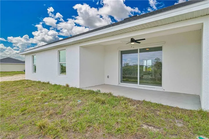 Back of property with stucco siding, a patio, ceiling fan, and a lawn