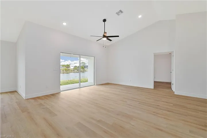 Unfurnished room featuring recessed lighting, light wood finished floors, lofted ceiling, ceiling fan, and a water view