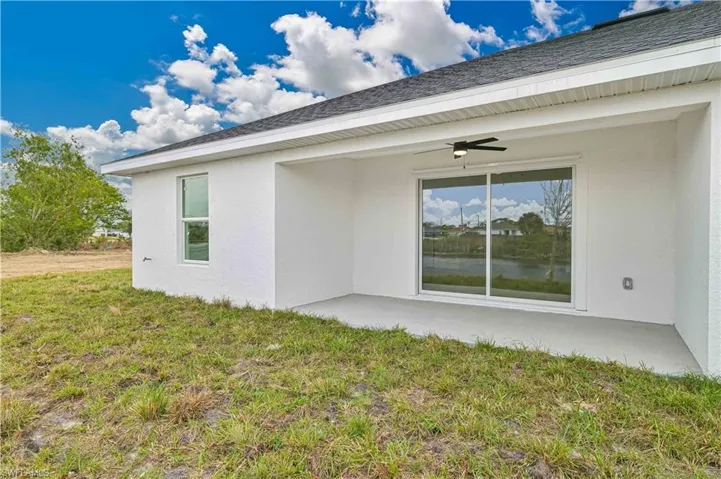 Back of property with a ceiling fan, stucco siding, a yard, and a patio