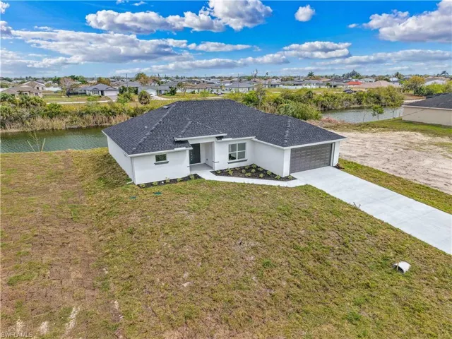 Single story home featuring a front yard, a garage, a water view, and stucco siding