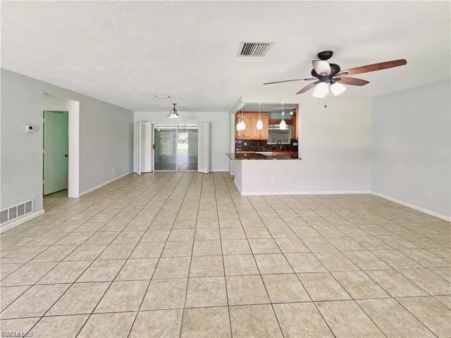 Unfurnished living room with a textured ceiling, light tile patterned floors, and ceiling fan