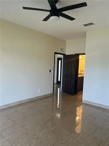 Empty room featuring ceiling fan, light marble finish flooring, and baseboards