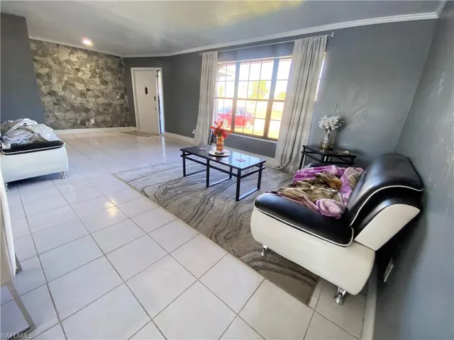Living room featuring crown molding and light tile patterned flooring