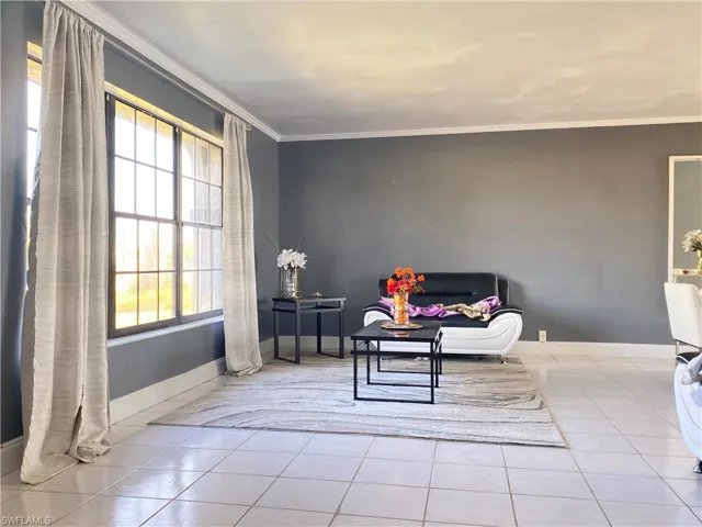 Living area featuring plenty of natural light, light tile patterned floors, and crown molding