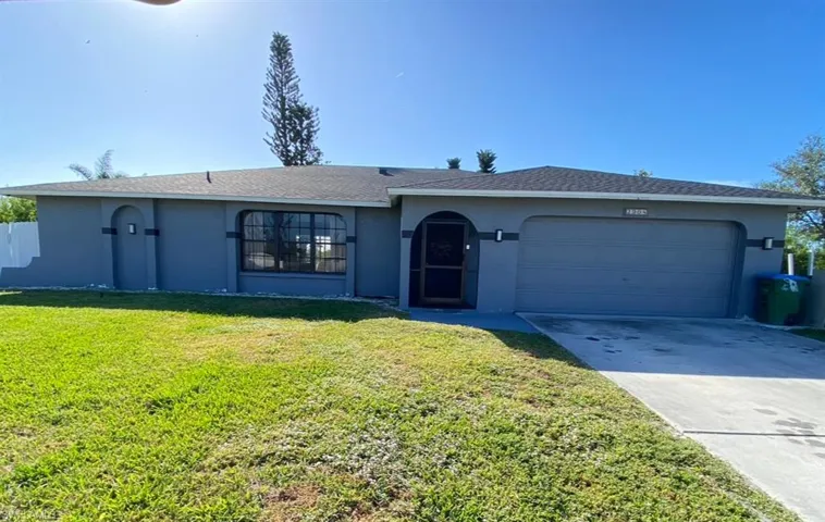 Single story home with a garage and a front lawn