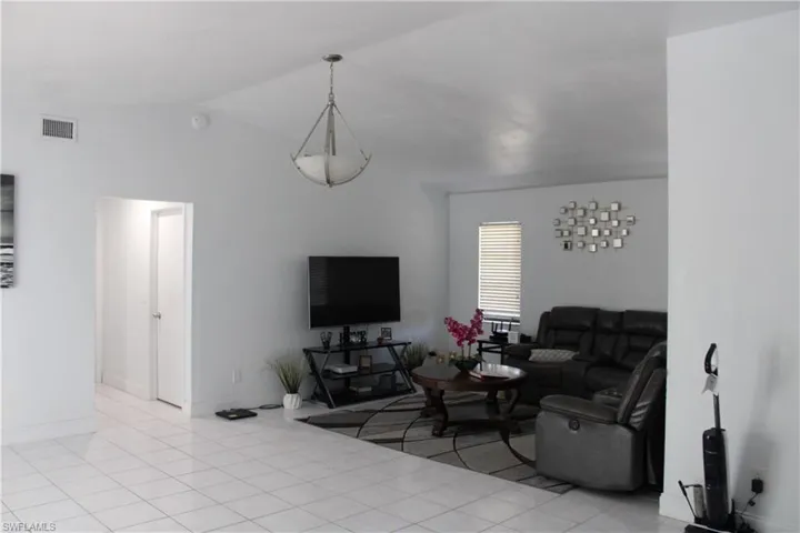 Living room featuring light tile patterned floors and lofted ceiling