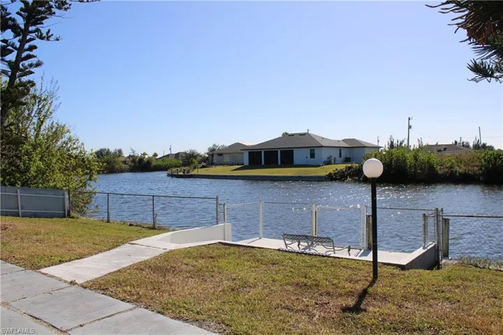 View of dock with a lawn and a water view
