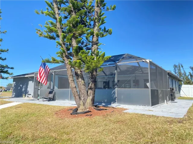 View of side of property with a patio area, a lanai, and a lawn