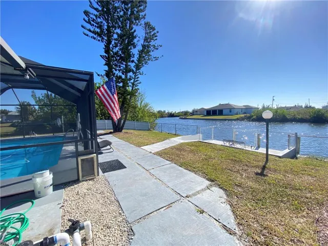 View of yard with a fenced in pool, glass enclosure, a patio area, and a water view