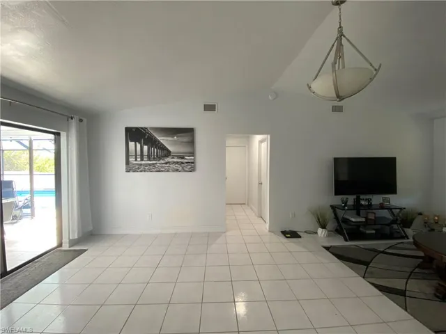 living room with light tile patterned flooring and vaulted ceiling