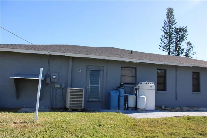 Rear view of property with cooling unit and a yard