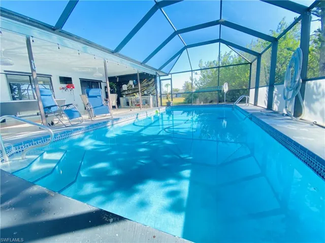 View of swimming pool featuring glass enclosure and a patio