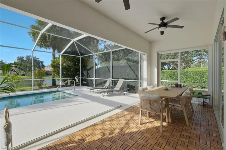Screened lanai featuring a swimming pool, wood-finish flooring, and two ceiling fans