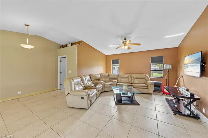 Tiled living room featuring vaulted ceiling and ceiling fan