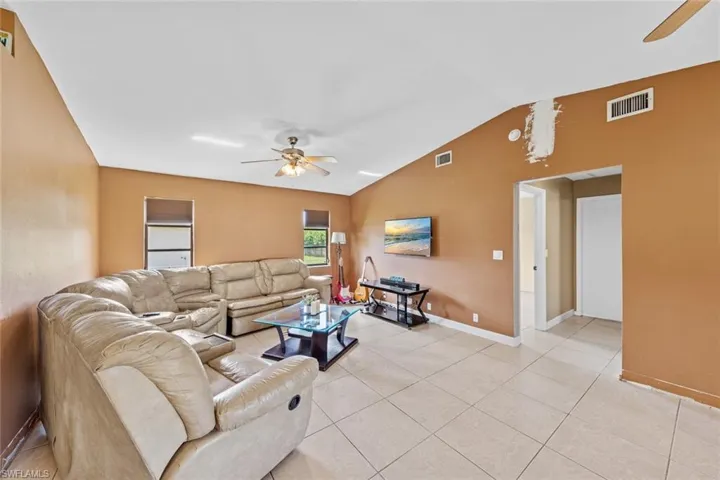 Tiled living room with lofted ceiling and ceiling fan