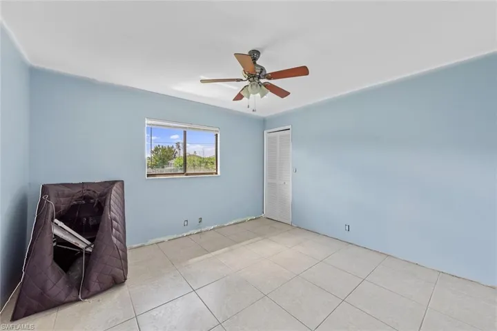 Empty room featuring ceiling fan and light tile patterned floors