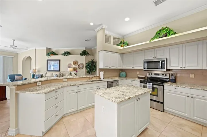 Spacious kitchen with granite counter tops, glass tile backsplash, stainless steel appliances, and raised bar.