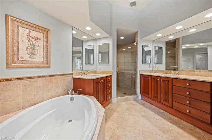 Primary bathroom with updated 36" European cherry cabinets, marble counter tops, Kohler sinks, faucets, and toilets. Updated porcelain tile floors, shower walls and tub deck. Updated Kohler soaking tub.