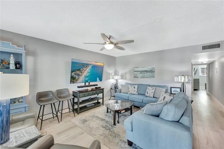 Living room with a ceiling fan, wood finished floors, and a textured ceiling