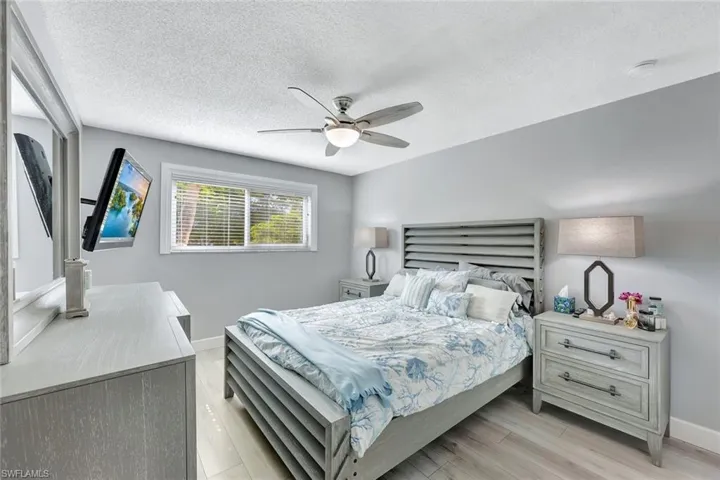 Bedroom with a textured ceiling, light wood-style flooring, and a ceiling fan