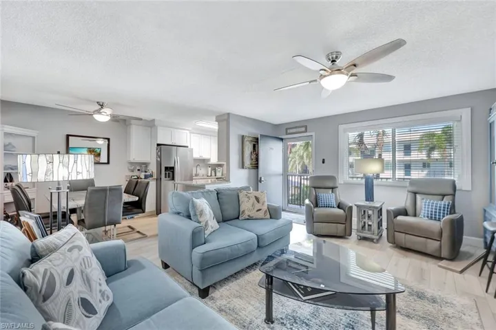 Living room featuring ceiling fan, a textured ceiling, and light wood finished floors