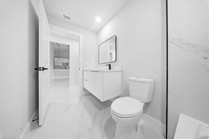 Full bathroom featuring vanity and light marble finish flooring