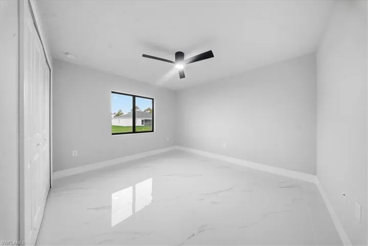 Unfurnished bedroom featuring light marble finish floors, a ceiling fan, and a closet