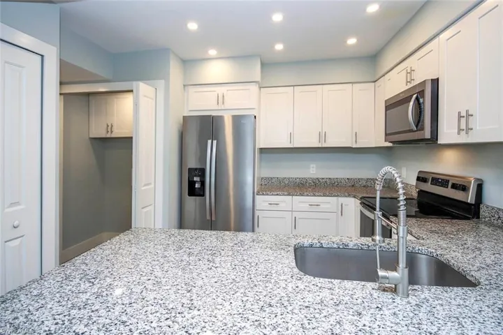 SS appliances with white shaker cabinets and granite counters