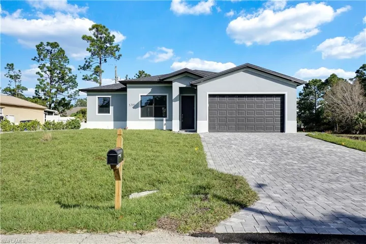 Single story home with stucco siding, a front yard, decorative driveway, and a garage