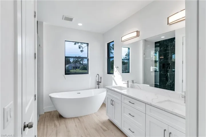Full bath with a shower stall, a soaking tub, double vanity, light wood-style flooring, and recessed lighting