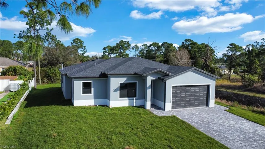 Ranch-style house featuring a front lawn, stucco siding, roof with shingles, decorative driveway, and a garage