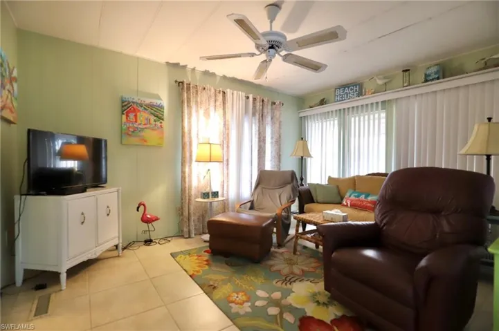 Living room with light tile patterned flooring and ceiling fan